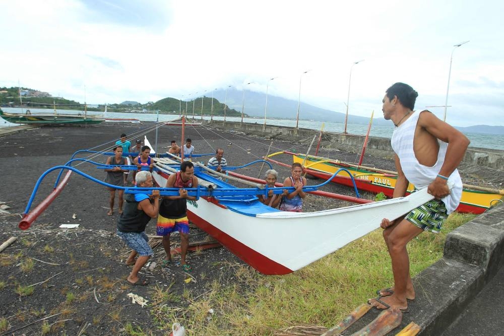 Residents and fishermen carry a wooden fishing boat to a safer place at a village in Legaspi City, Albay province, south of Manila on Saturday. AFP