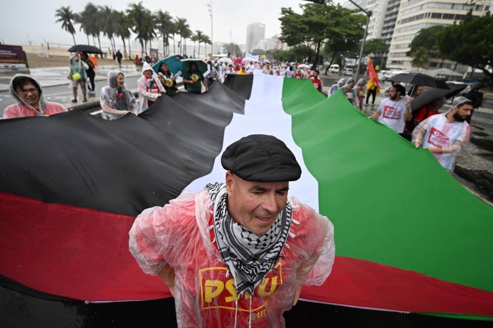 Members of social movements hold a large Palestinian flag during a march in support of the Palestinian people at Copacabana beach in Rio de Janeiro, Brazil, on Saturday, ahead of the G20 Summit. AFP