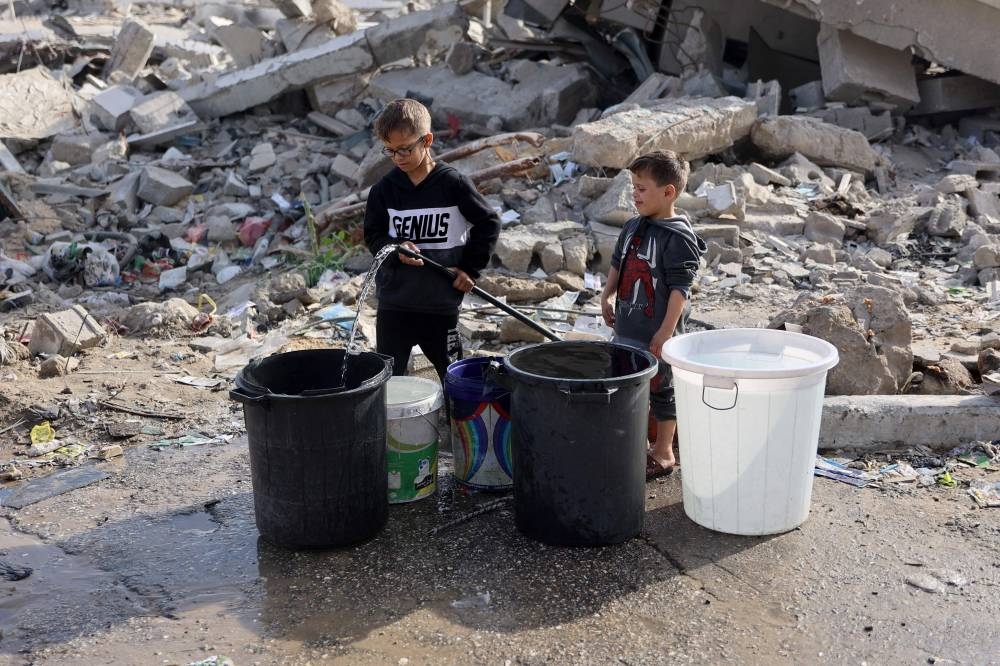 Palestinian children fill containers with water in Gaza City. 