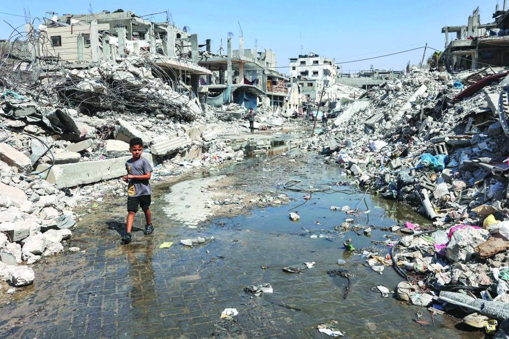 A boy walks through a puddle of sewage water past mounds of trash and rubble along a street in the Jabalia camp for Palestinian refugees in the northern Gaza Strip.