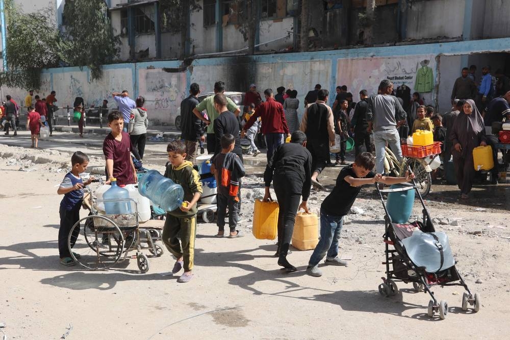 Displaced Palestinian children transport clean water in front of a UN school-turned shelter in the Nasser district of Gaza City, in the northern Gaza Strip. 