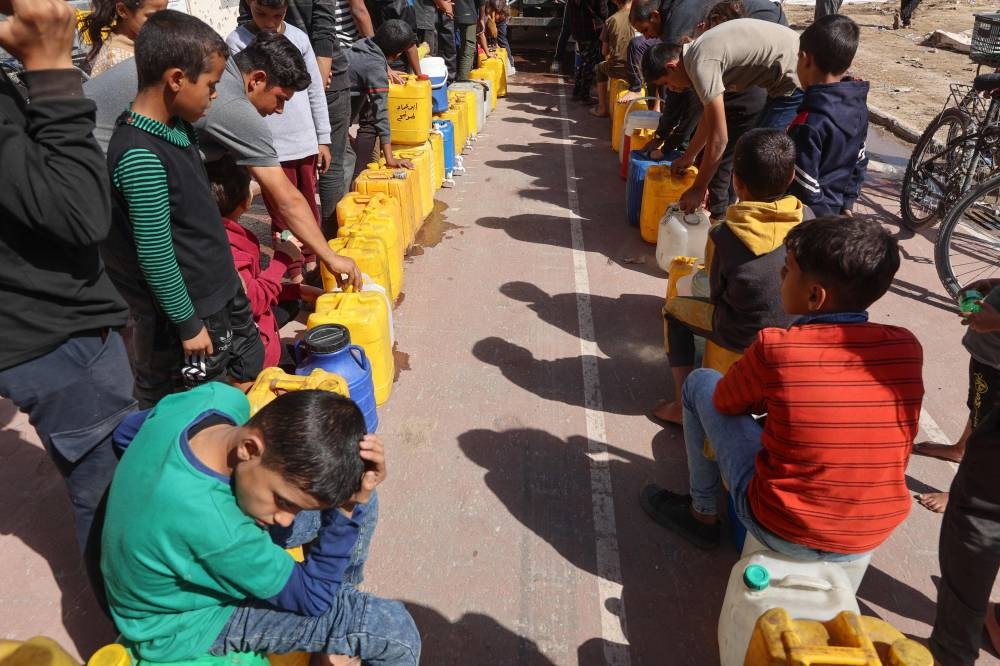 Displaced Palestinian children who fled Israeli army operations in the northern Gaza Strip, queue for clean water at the Yarmouk Sports Stadium, once a football arena, where they found shelter in a tent encampment in Gaza City.