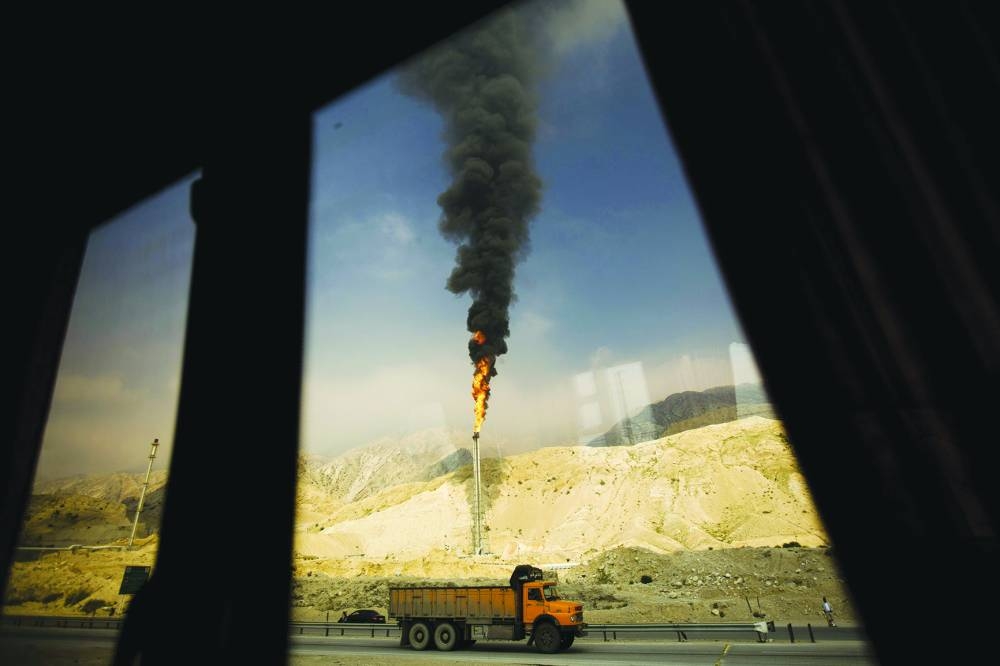 A gas flame is seen through a bus window in the South Pars gas field facilities in the southern Iranian port of Assaluyeh. Iran is facing wide-reaching power outages — including scheduled blackouts across Tehran and other major cities in recent days — as US sanctions restrict investment.