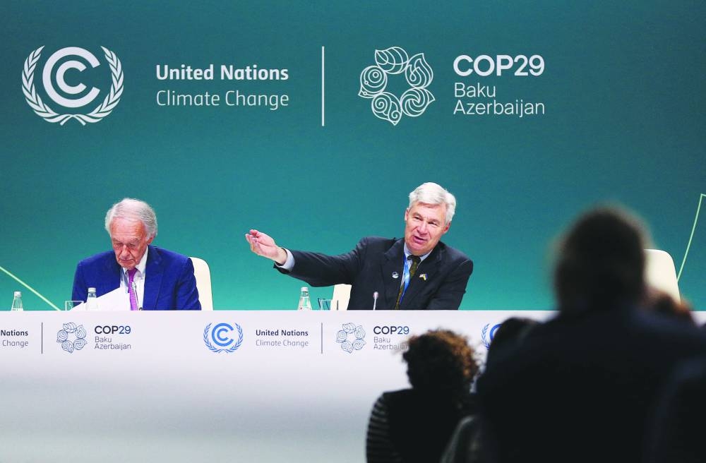 US Senators Sheldon Whitehouse and Ed Markey attend a session of the UN climate change conference COP29 in Baku yesterday. Right: An environmental activist takes part in a protest to urge world leaders to commit to a strong climate finance deal. (Reuters)