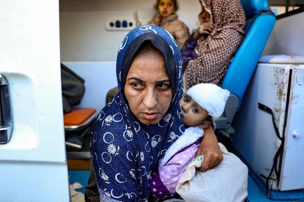 Palestinian women and children injured in an Israeli strike, wait in an ambulance in front of the al-Aqsa Martyrs Hospital in Deir Al-Balah in the central Gaza Strip, on Sunday. AFP