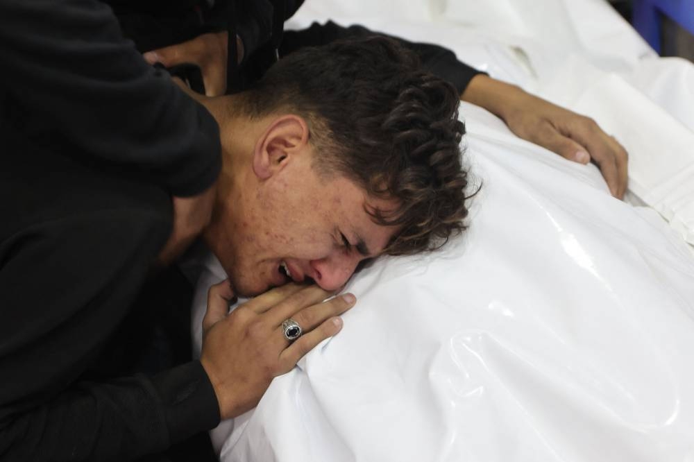 A youth mourns by the covered body of a relative killed in an Israeli strike that destroyed a house on al-Jalaa street in central Gaza City, on Monday. AFP
