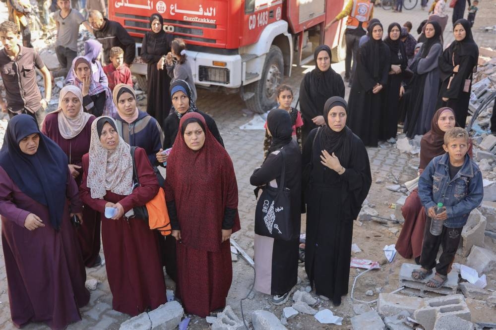 Women react near the rubble of a house destroyed in an Israeli strike as rescuers search for casualties on al-Jalaa street in central Gaza City, on Monday. AFP