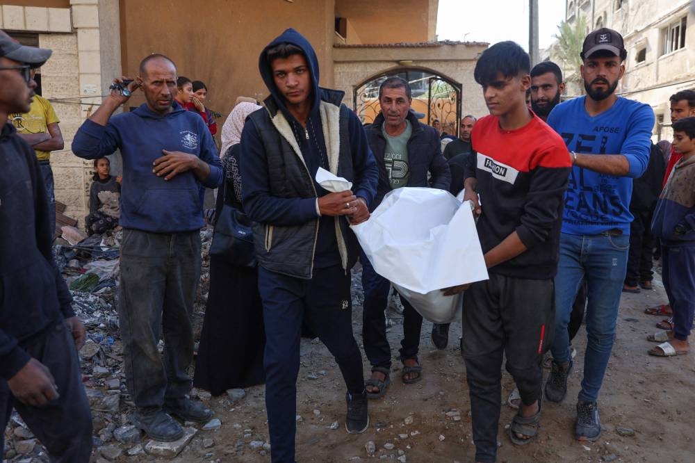 People carry the covered body of a person pulled from the rubble of a house destroyed in an Israeli strike on al-Jalaa street in central Gaza City, on Monday. AFP