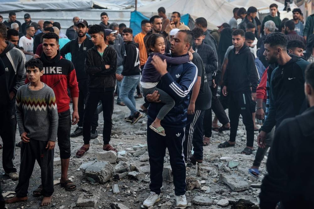 A man holds a crying child as displaced Palestinians check the destruction following an Israeli strike that hit a UN-run school where people had taken refuge, in the Nusseirat refugee camp in the central Gaza Strip on Wednesday. AFP