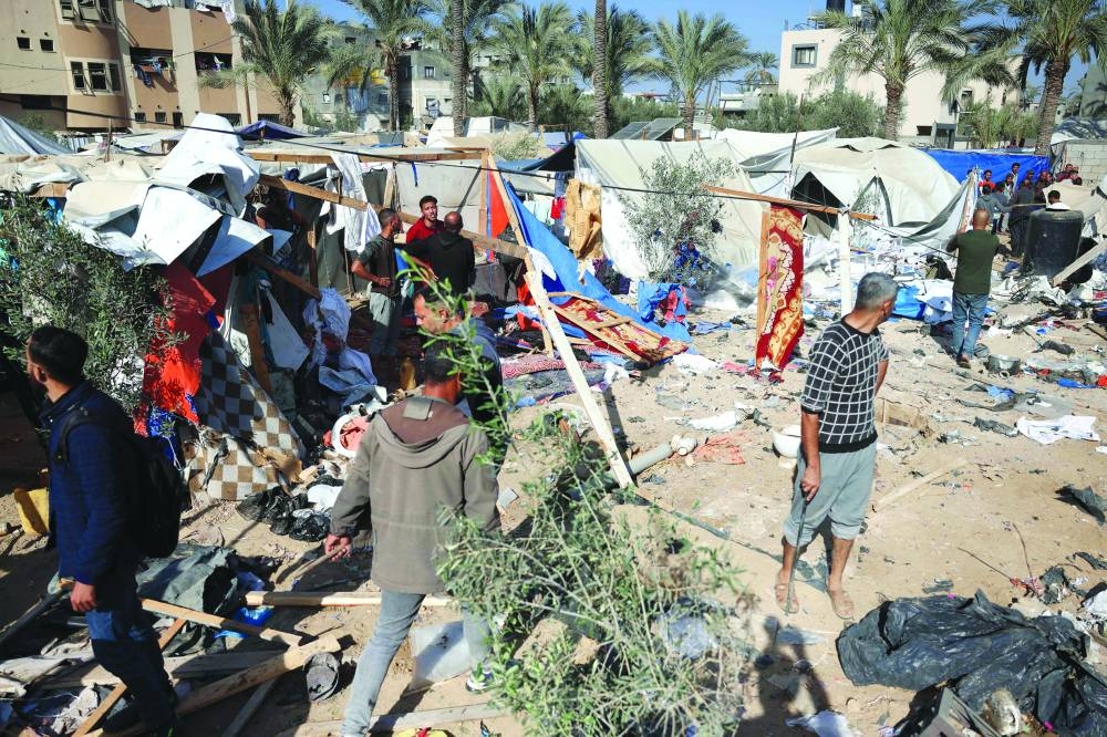 Displaced Palestinians gather around the remains of a tent that was destroyed in an Israeli strike, west of Deir el-Balah in the central Gaza Strip on Thursday 