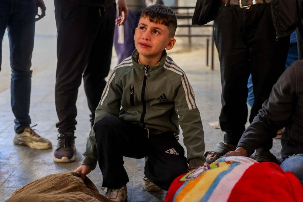 A Palestinian boy mourns over the bodies of victims of an Israeli strike the previous night south of Gaza City, at Al-Ahli Arab hospital, also known as the Baptist hospital, in Gaza City on Friday. AFP