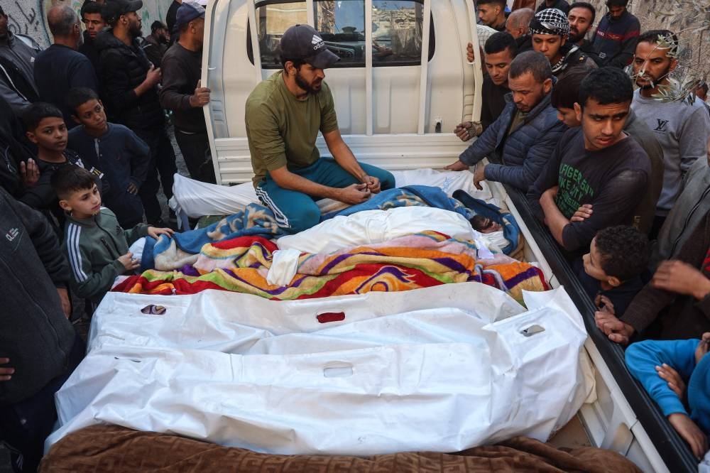 Palestinians watch as the bodies of people killed in a Israeli strike the previous night are brought to Al-Ahli Arab hospital, also known as the Baptist hospital, in Gaza City Friday. AFP
