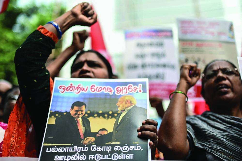 Members of the Communist Party of India (CPI-M) hold a placard as they take part in a protest calling for the tycoon’s arrest over corruption allegations by US prosecutors.