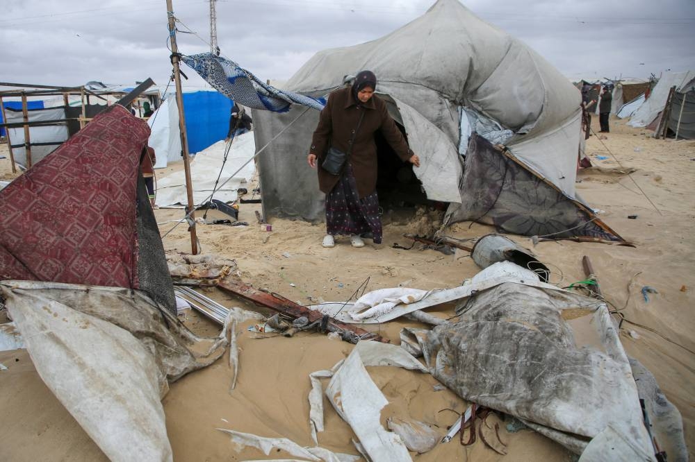 A displaced Palestinian woman inspects a flooded tent following rising sea levels and heavy rainfall, in Khan Younis in the southern Gaza Strip, on Monday. REUTERS