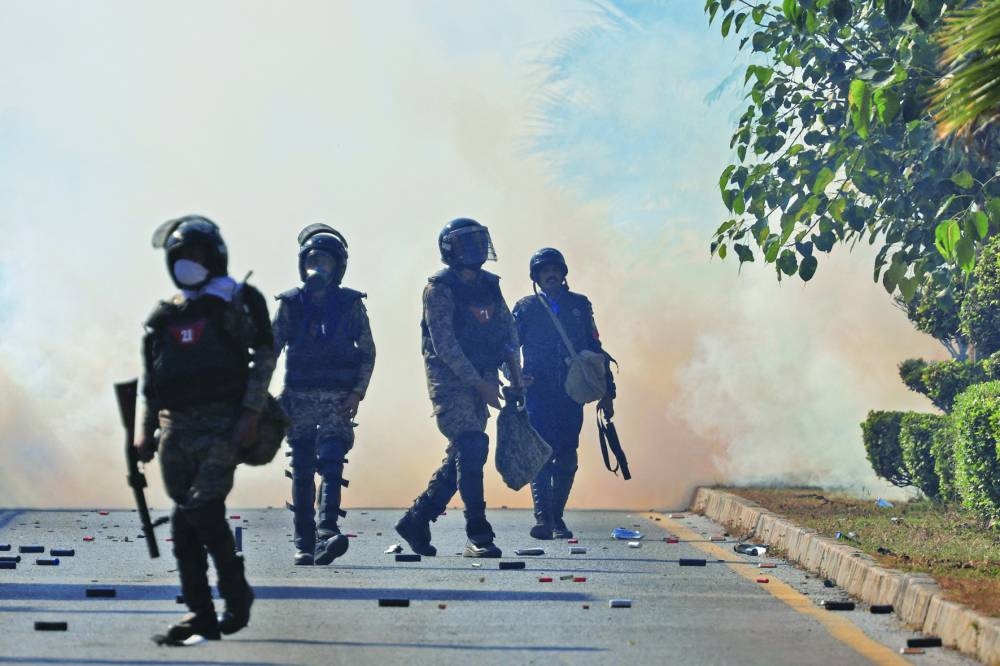 Security force personnel walk as smoke billows from tear gas shells fired to stop the protesters. ( Reuters)