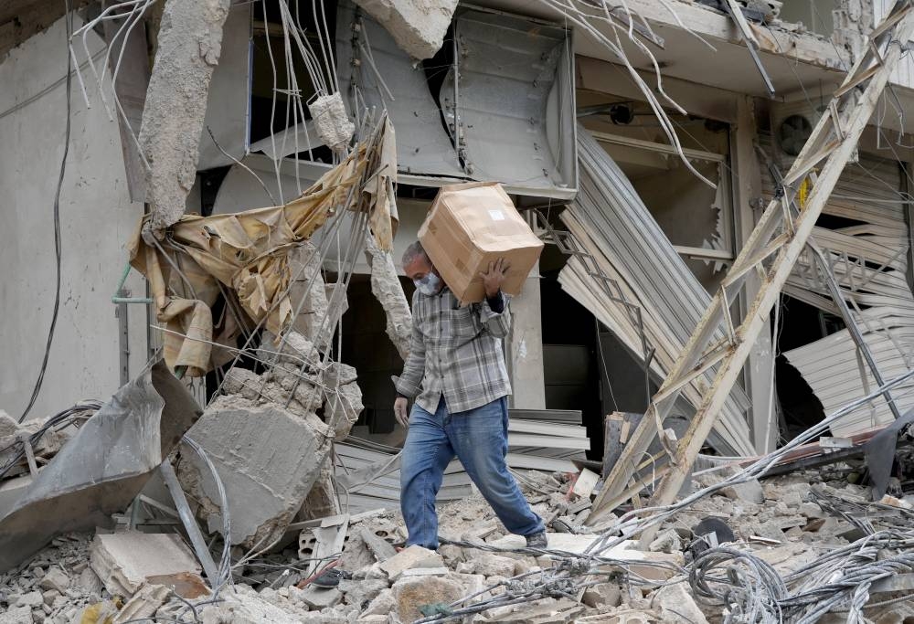 A man carries a box as he walks on the rubble of a damaged building in Beirut's southern suburbs, on Wednesday. REUTERS