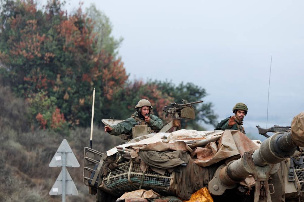 Israeli soldiers gesture from an Israeli military vehicle near Israel's border with Lebanon in northern Israel, on Wednesday. REUTERS