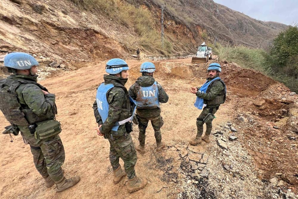 UNIFIL soldiers stand next to a pit caused by an Israeli airstrike on a road in the Khardali area in southern Lebanon, on Wednesday. AFP