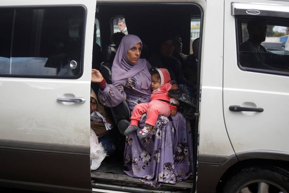 A woman holds a child as people return, in Tyre, Lebanon, on Wednesday. REUTERS