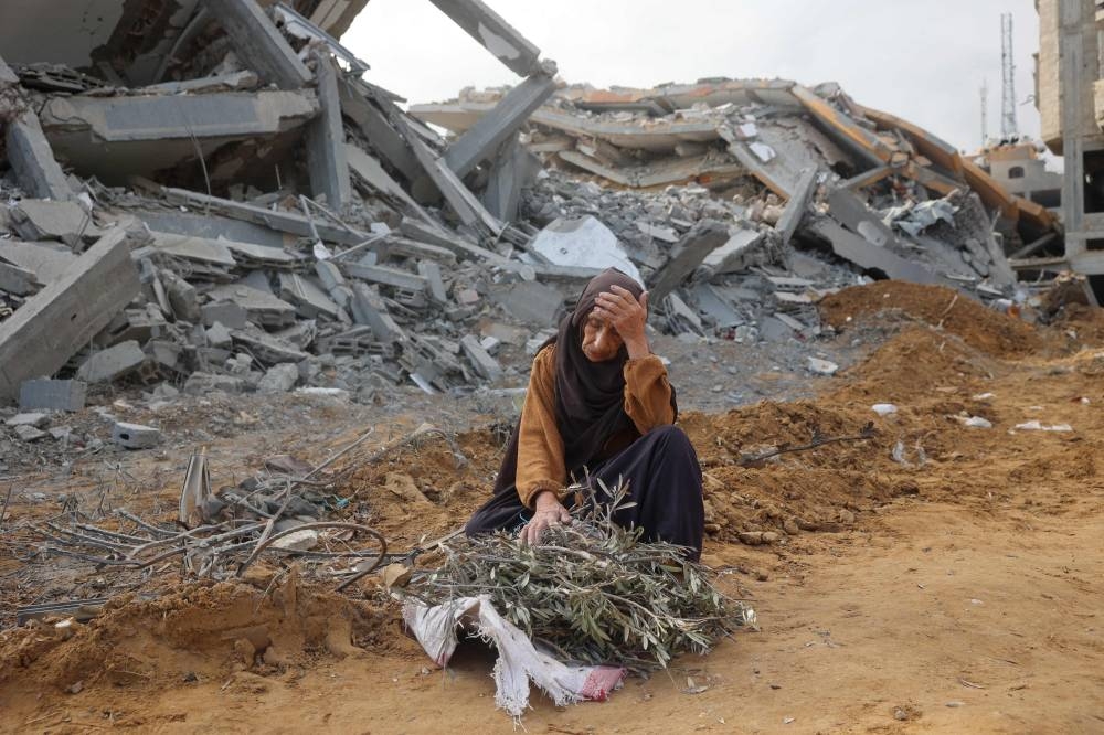 A elderly woman sits in front of a destroyed building to take a rest as she collects tree branches to light a fire in Nuseirat in the central Gaza Strip after Israeli shelling of the camp stopped on Friday. AFP