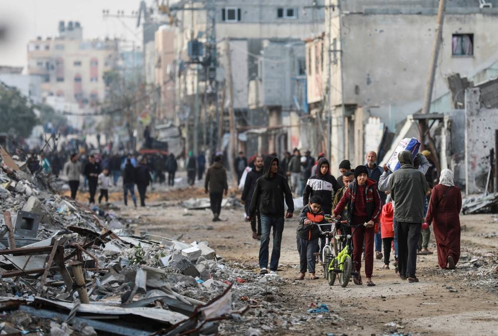 Palestinians walk next to rubble after Israeli forces withdrew from a part of Nuseirat, in Nuseirat, central Gaza Strip, on Friday. REUTERS