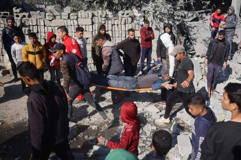 Palestinians evacuate a wounded man from the site of an Israeli strike that targeted a home in the Bureij refugee camp in the central Gaza Strip on Monday. AFP