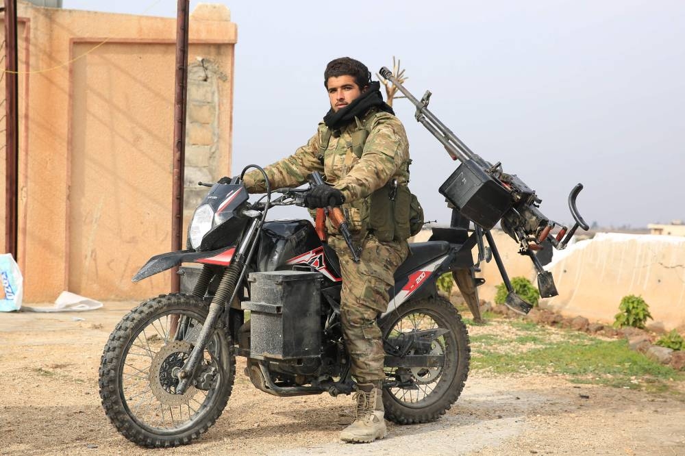 An anti-government fighter rides his motorcycle in city of al-Rastan in Syria's west-central province of Homs on Saturday, as anti-government forces make their way to Homs. AFP