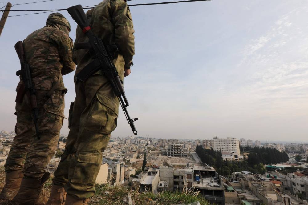 Anti government forces keep watch at a position overlooking Hama days after they captured and took control of the central Syrian city, on Saturday. AFP