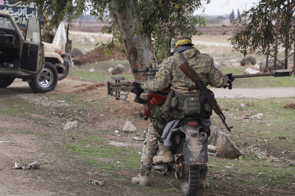 Rebel fighters sit on a motorcycle in Homs countryside. REUTERS