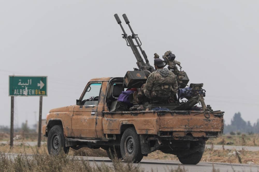 A rebel fighter sits on the back of a vehicle in Homs countryside. REUTERS