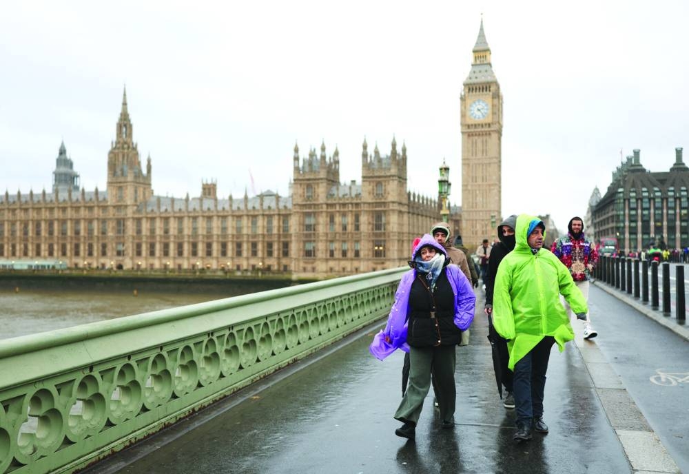 Tourists wearing raincoats walk on Westminster Bridge after Storm Darragh hit the country, in London.