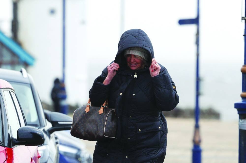 A woman covers herself after Storm Darragh hit the country, in Porthcawl, Wales.