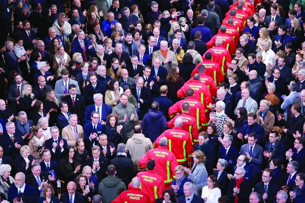 
Firefighters, rescuers and builders involved in the restoration of Notre-Dame Cathedral parade during the ceremony to mark the reopening of landmark cathedral. (AFP) 