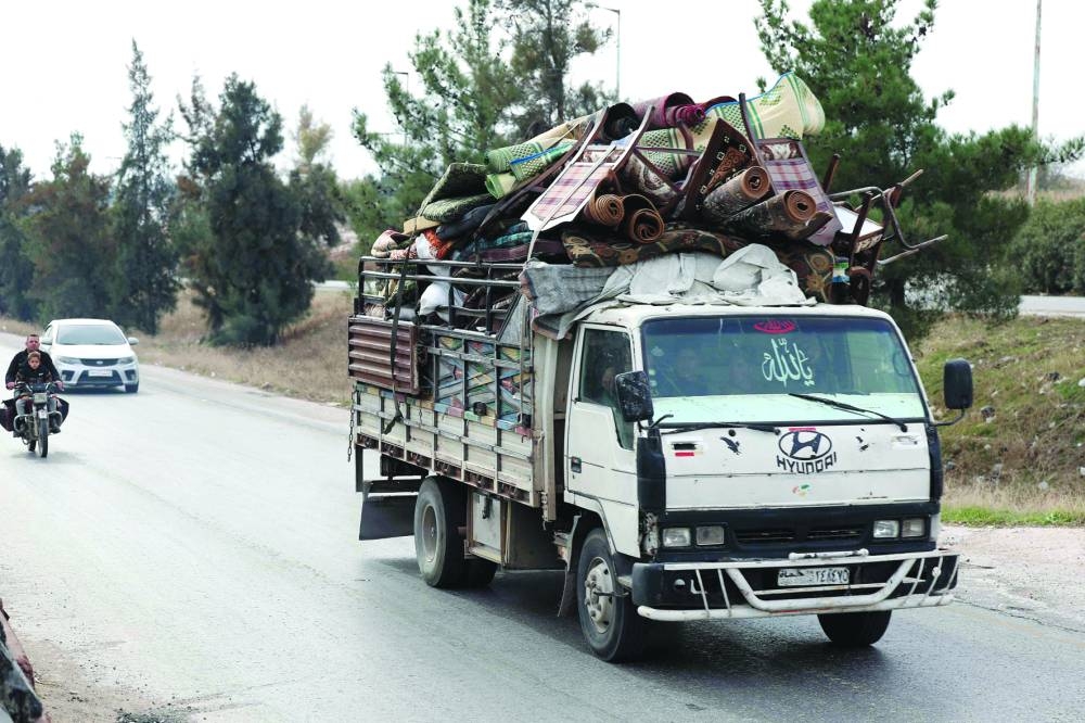 
People ride a vehicle loaded with belongings in Syria’s Hama governorate after anti-government forces took control of the area, yesterday. 