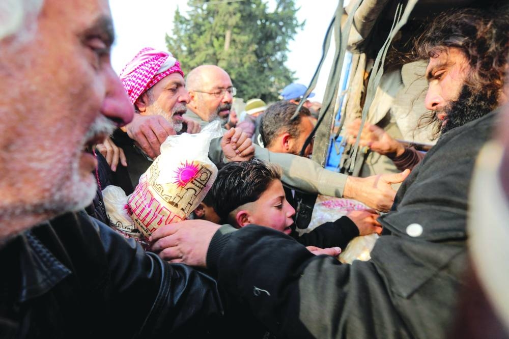 Anti-government forces distribute bread to the residents of Hama, days after they captured and took control of the central Syrian city, yesterday.