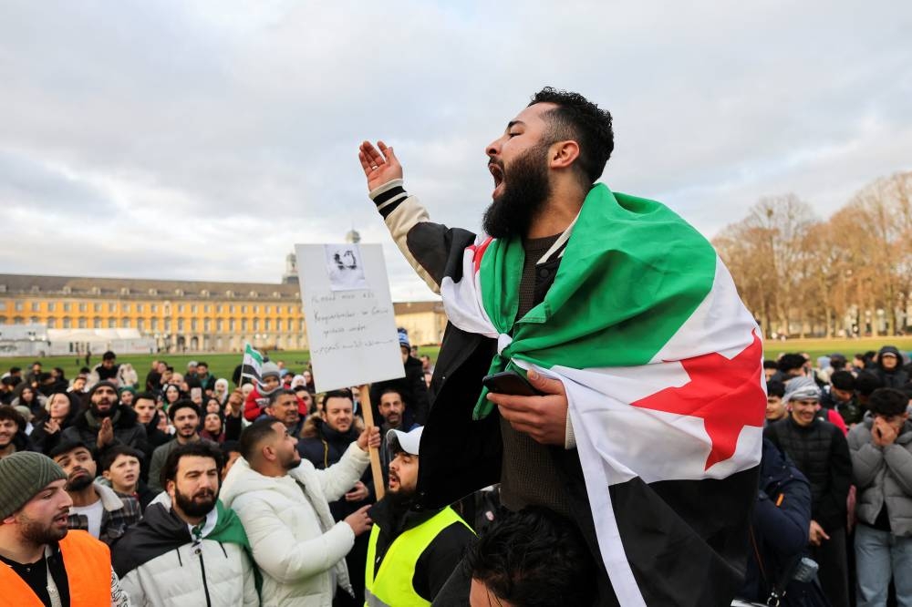 A man draped in a Syrian opposition flag reacts, as people gather on the streets, after Syrian rebels announced that they have ousted Syria's Bashar al-Assad, in Bonn, Germany, on Sunday. REUTERS