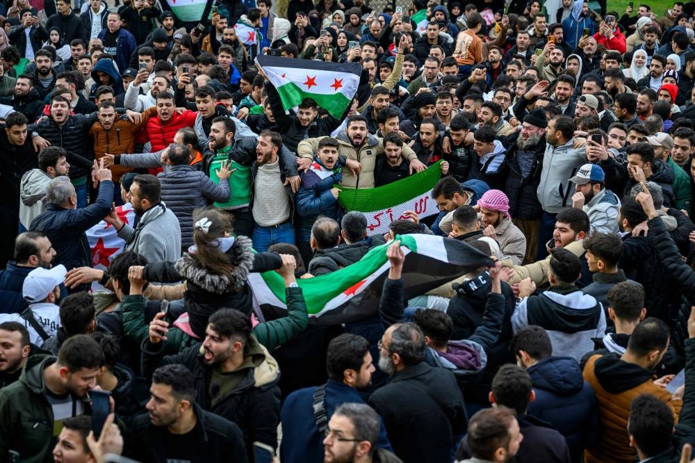 Syrian residents in Turkey wave Syrian opposition flags as they celebrate the end of the Baath rule in Syria after rebel fighters took control of Damascus overnight, at the Fatih Mosque, in Istanbul, on Sunday. AFP
