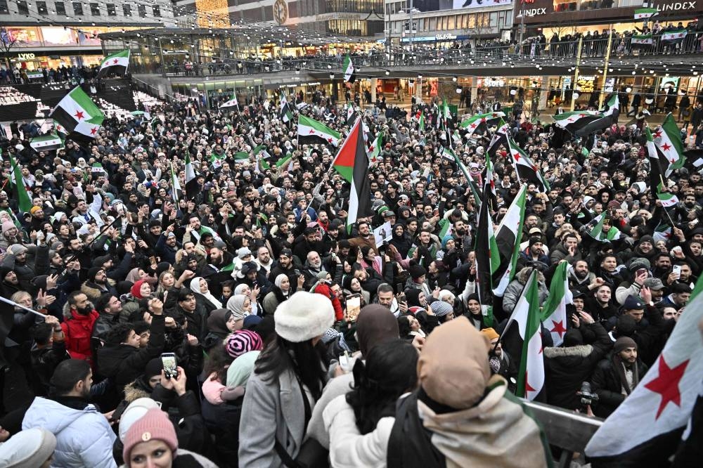 Members of the Syrian community hold Syrian flags as they rally on Sunday on Sergel's Square in Stockholm, Sweden, to celebrate the end of Syrian dictator Bashar al-Assad's rule. AFP