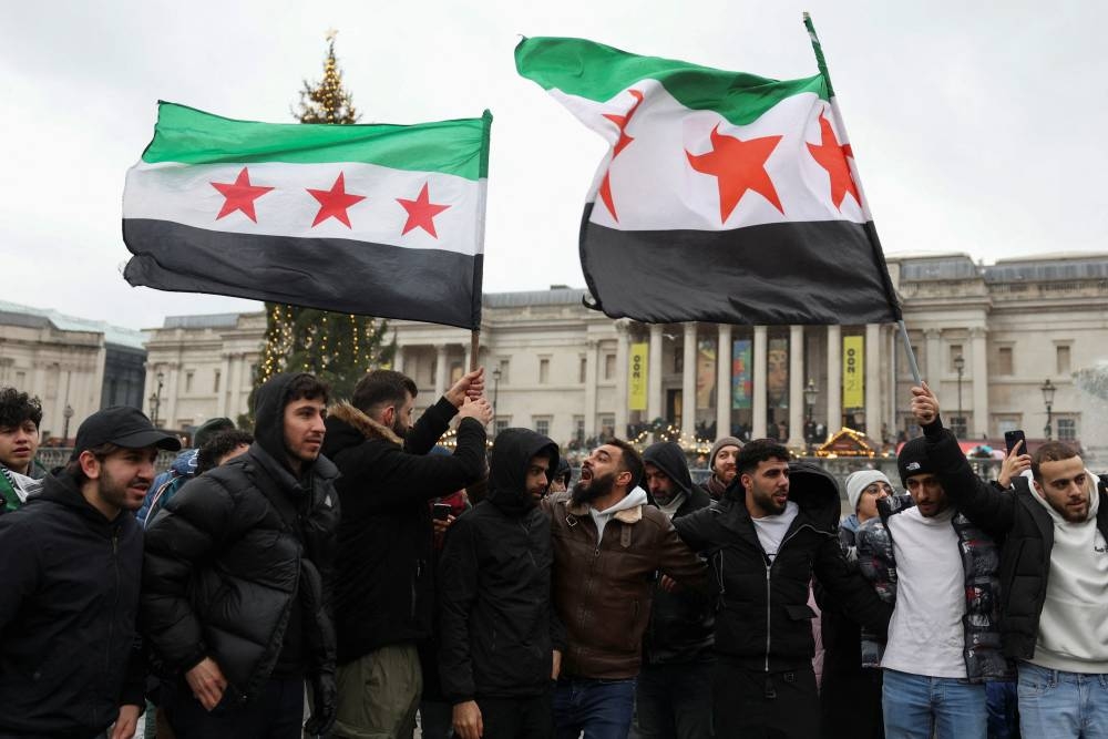 People wave Syrian opposition flags as they gather in Trafalgar Square, after Syrian rebels announced that they have ousted Syria's Bashar al-Assad, in London, Britain, on Sunday. REUTERS
