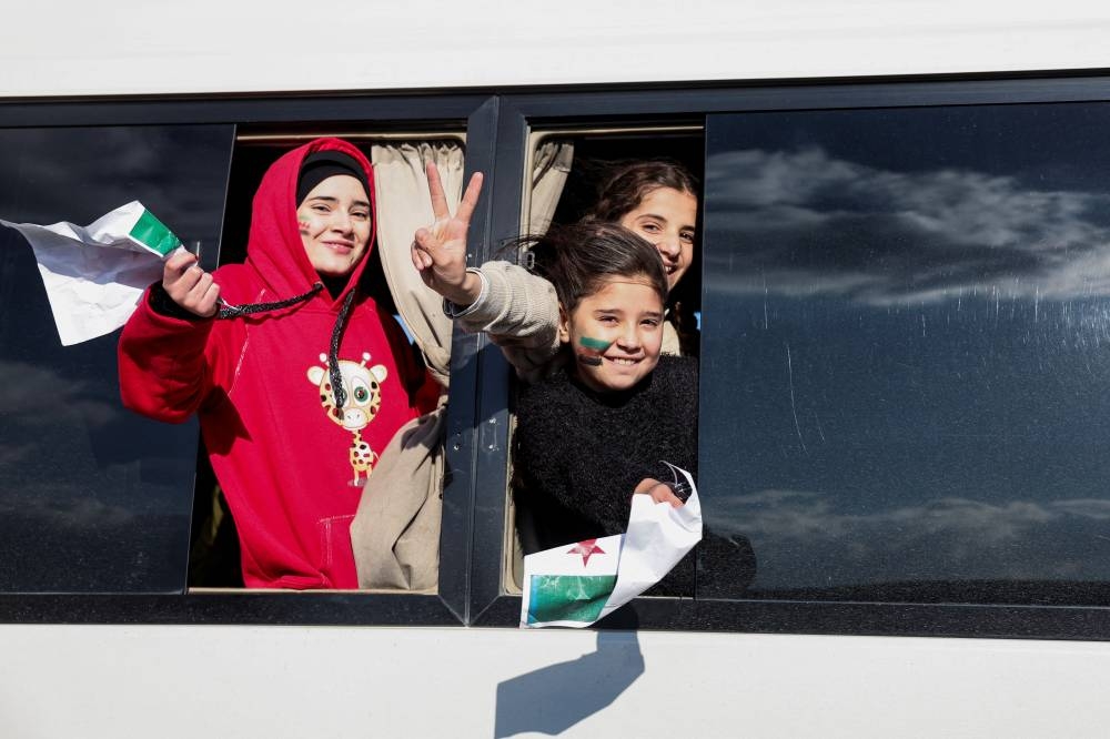 Syrians gesture from a bus as they are heading to Syria, after Syrian rebels announced that they have ousted President Bashar al-Assad, at Majdal Anjar in Bekaa, Lebanon, on Sunday. REUTERS