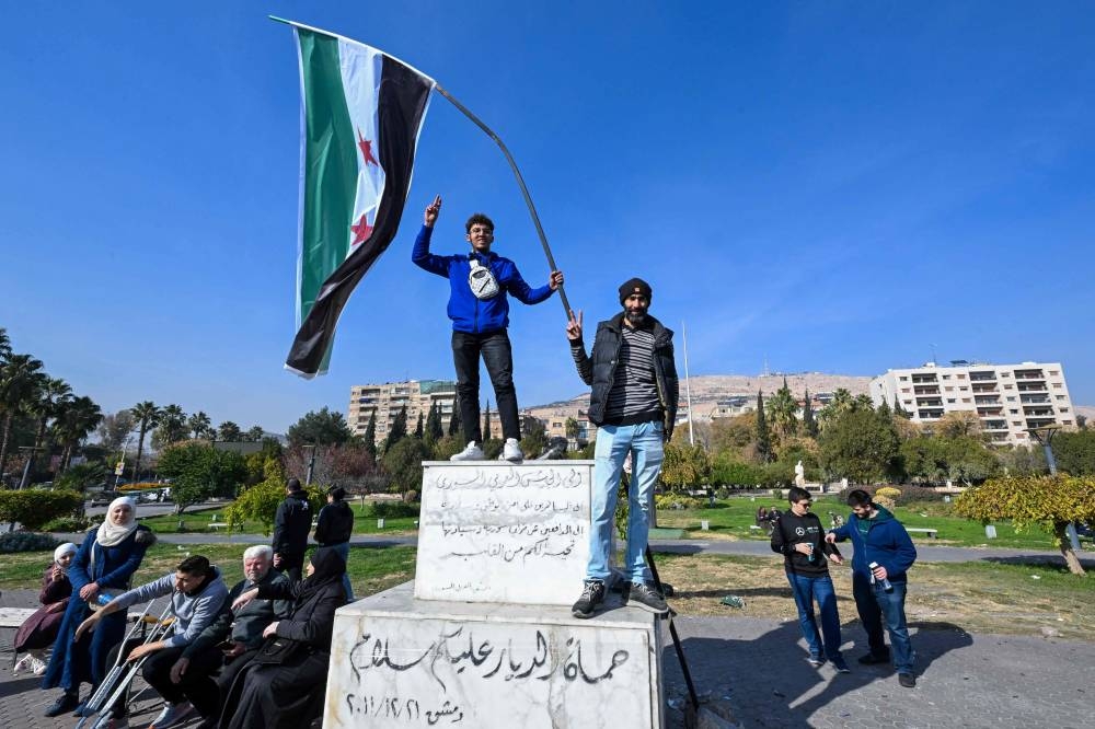 Two men pose with a Syrian opposition flag at Umayyad Square in Damascus, on Monday. AFP