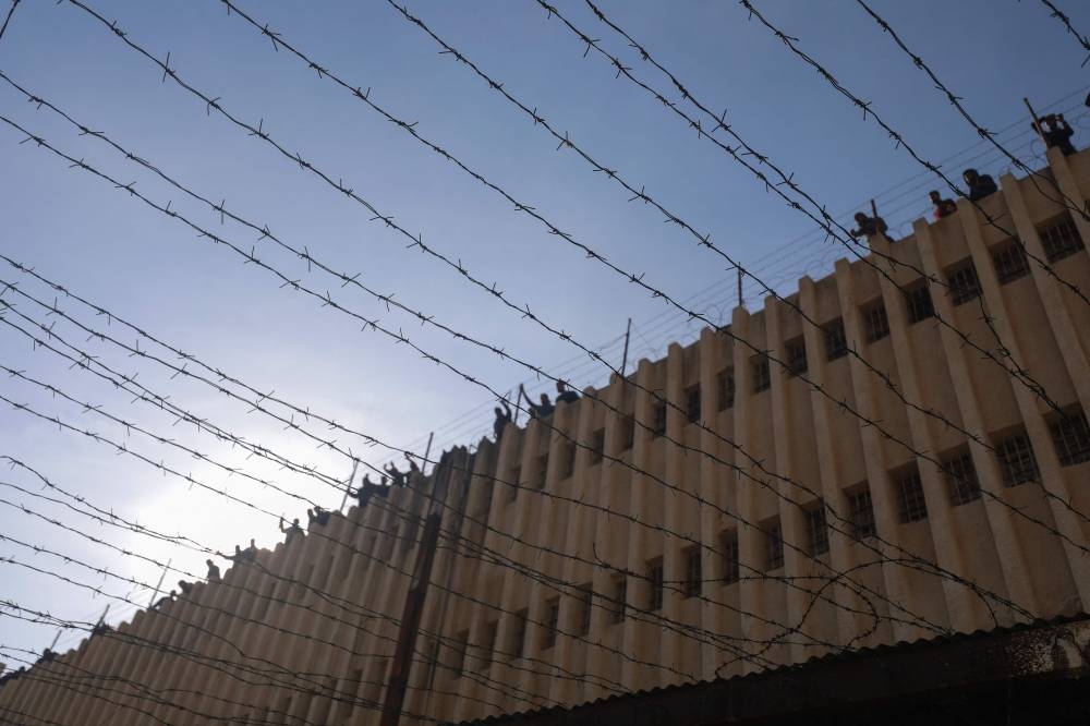 People stand on the roof of the Saydnaya prison as Syrian rescuers and experts search for potential hidden basements at the facility in Damascus, on Monday. AFP