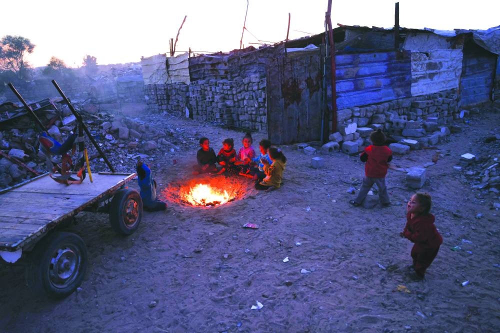 Children warm by the fire at a makeshift camp for displaced Palestinians in the Nahr al-Bared area in Khan Yunis, in the southern Gaza Strip on Monday. AFP