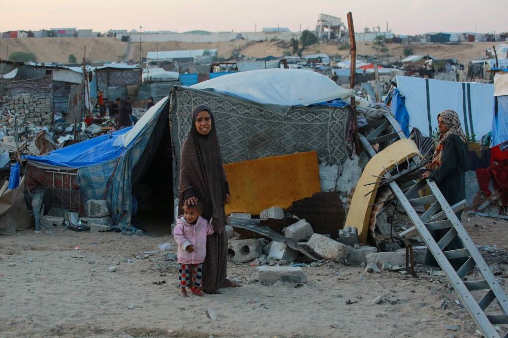 People stand outside their shelters at a makeshift camp for displaced Palestinians in the Nahr al-Bared area in Khan Yunis, in the southern Gaza Strip, on Monday. AFP