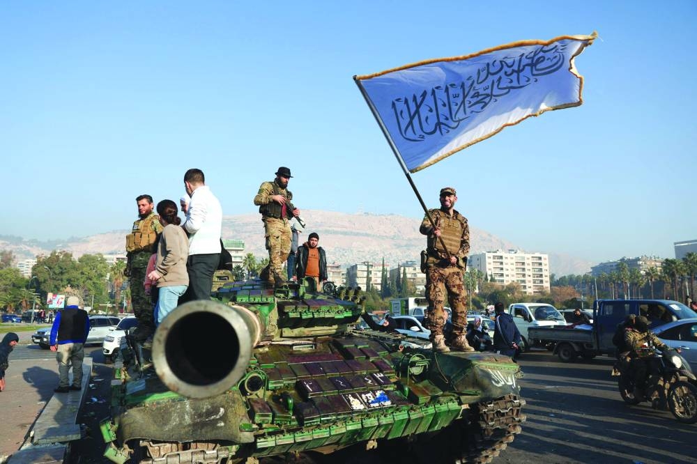 An anti-government fighter waves a flag from atop a tank in Damascus Monday.