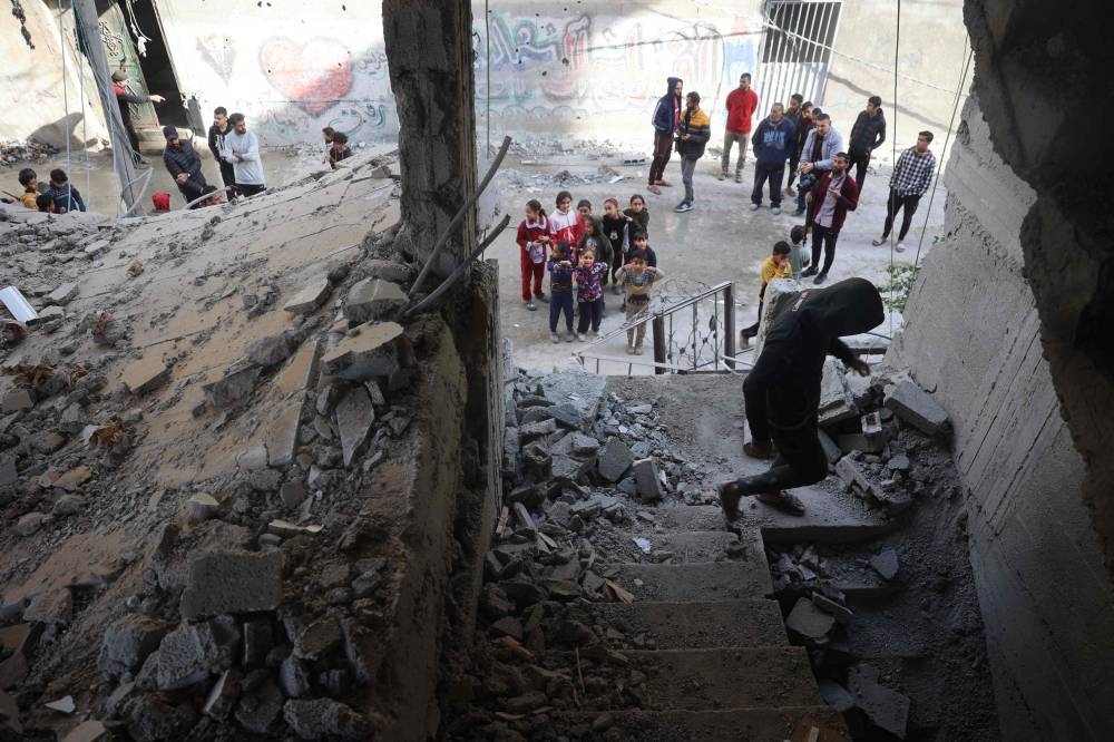 Palestinians check a building destroyed during an Israeli strike in the Nuseirat camp in the central Gaza Strip, on Tuesday. AFP