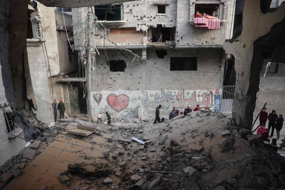 Palestinians stand next to a building destroyed during an Israeli strike in the Nuseirat camp in the central Gaza Strip, on Tuesday. AFP