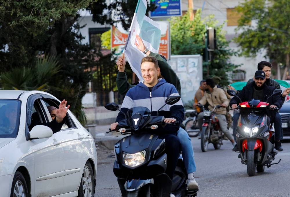 People hold the Syrian opposition flag as they celebrate, in Jableh, Latakia governorate, Syria, on Tuesday. REUTERS