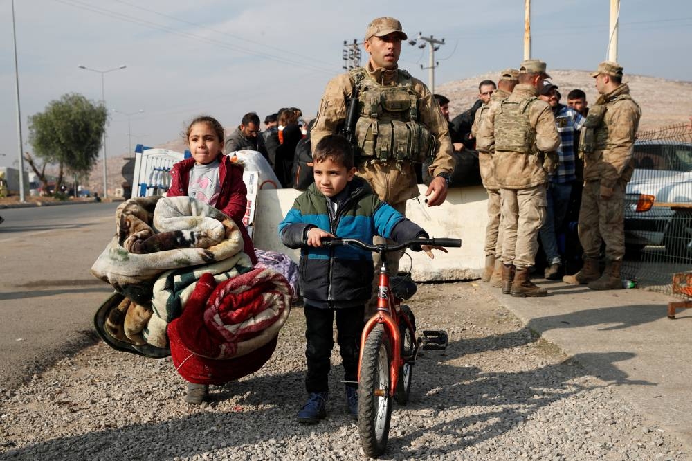 Syrian migrants wait at the Cilvegozu border gate to cross into Syria, in the Turkish town of Reyhanli in Hatay province, on Tuesday. REUTERS
