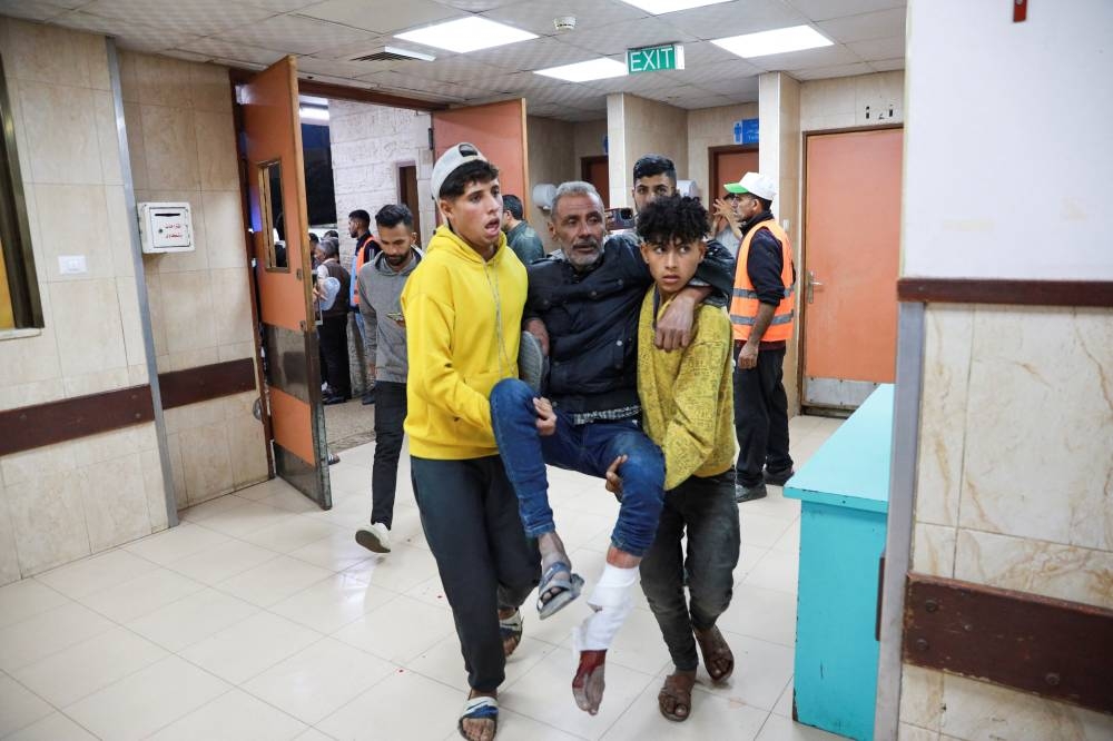 Palestinians carry a wounded man at a hospital, in the aftermath of an Israeli strike, in Deir Al-Balah in the central Gaza Strip, on Wednesday. REUTERS